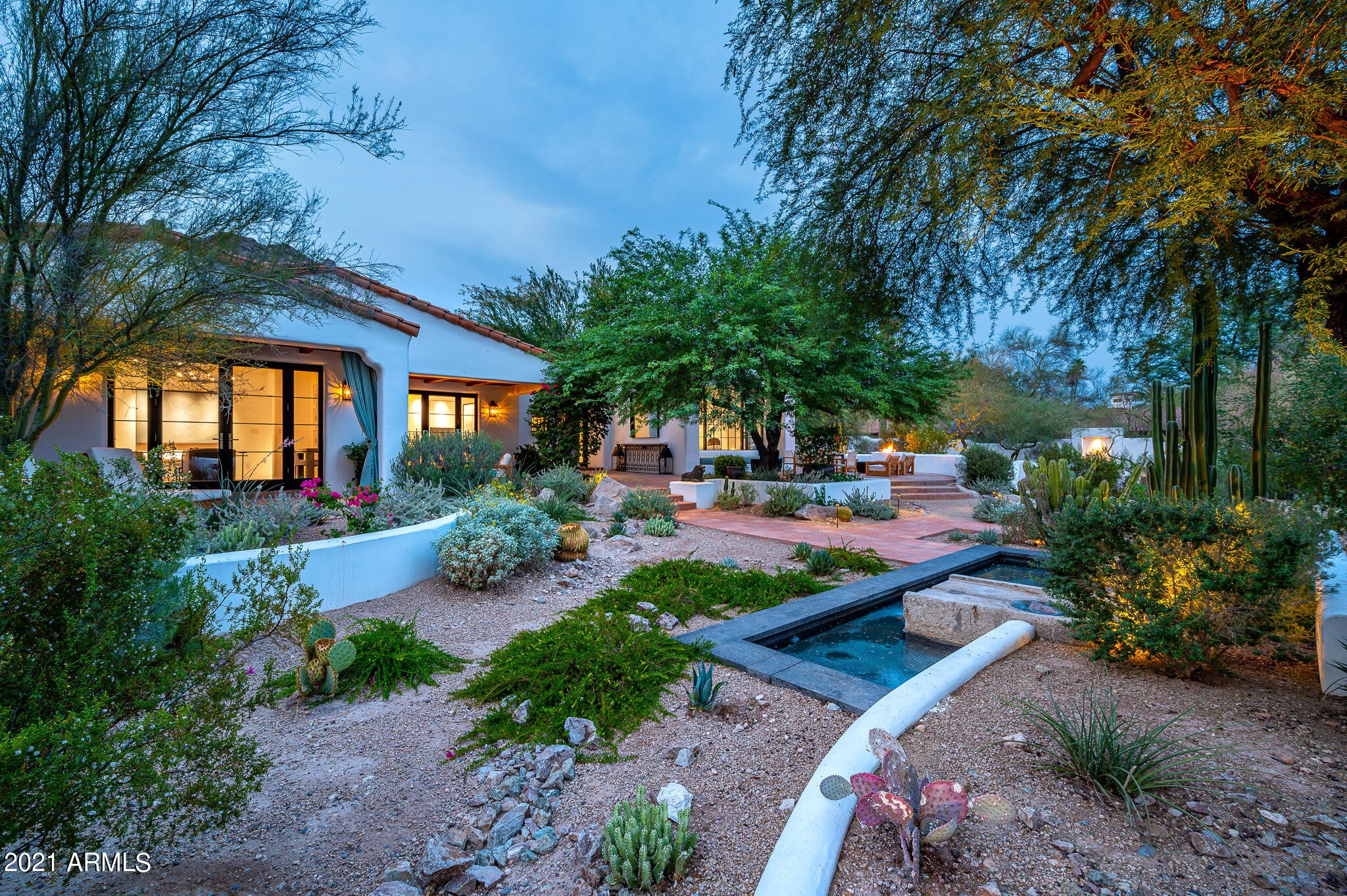 Desert home with a landscaped garden path and water feature in the evening
